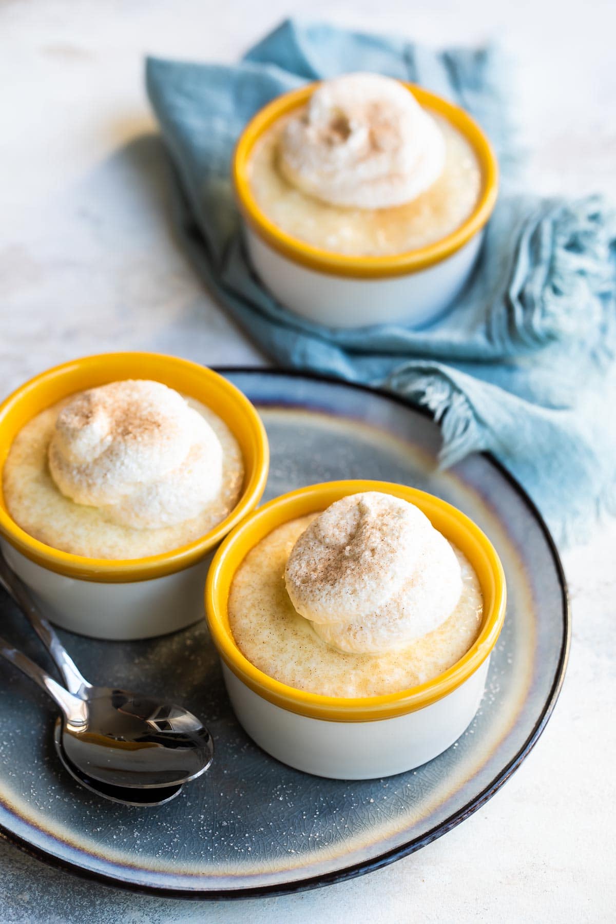 Three bowls of tapioca topped with whipped cream.