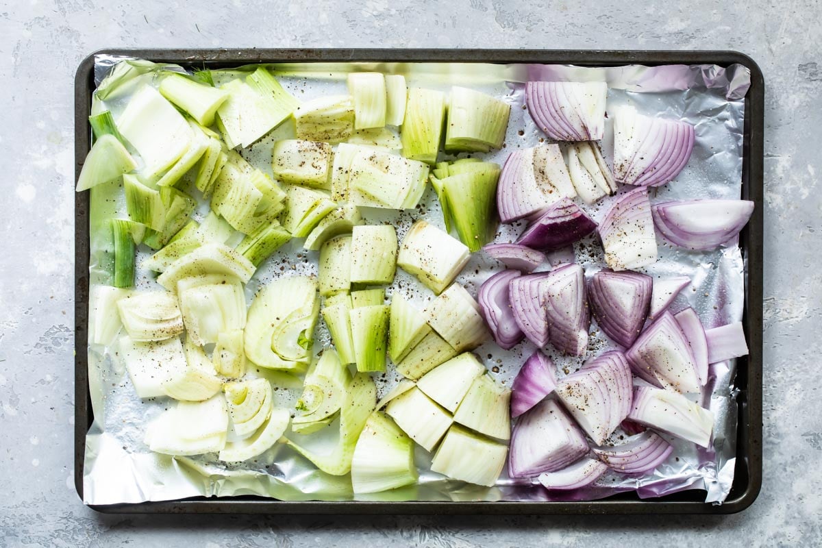 Uncooked fennel and onions on a baking sheet.