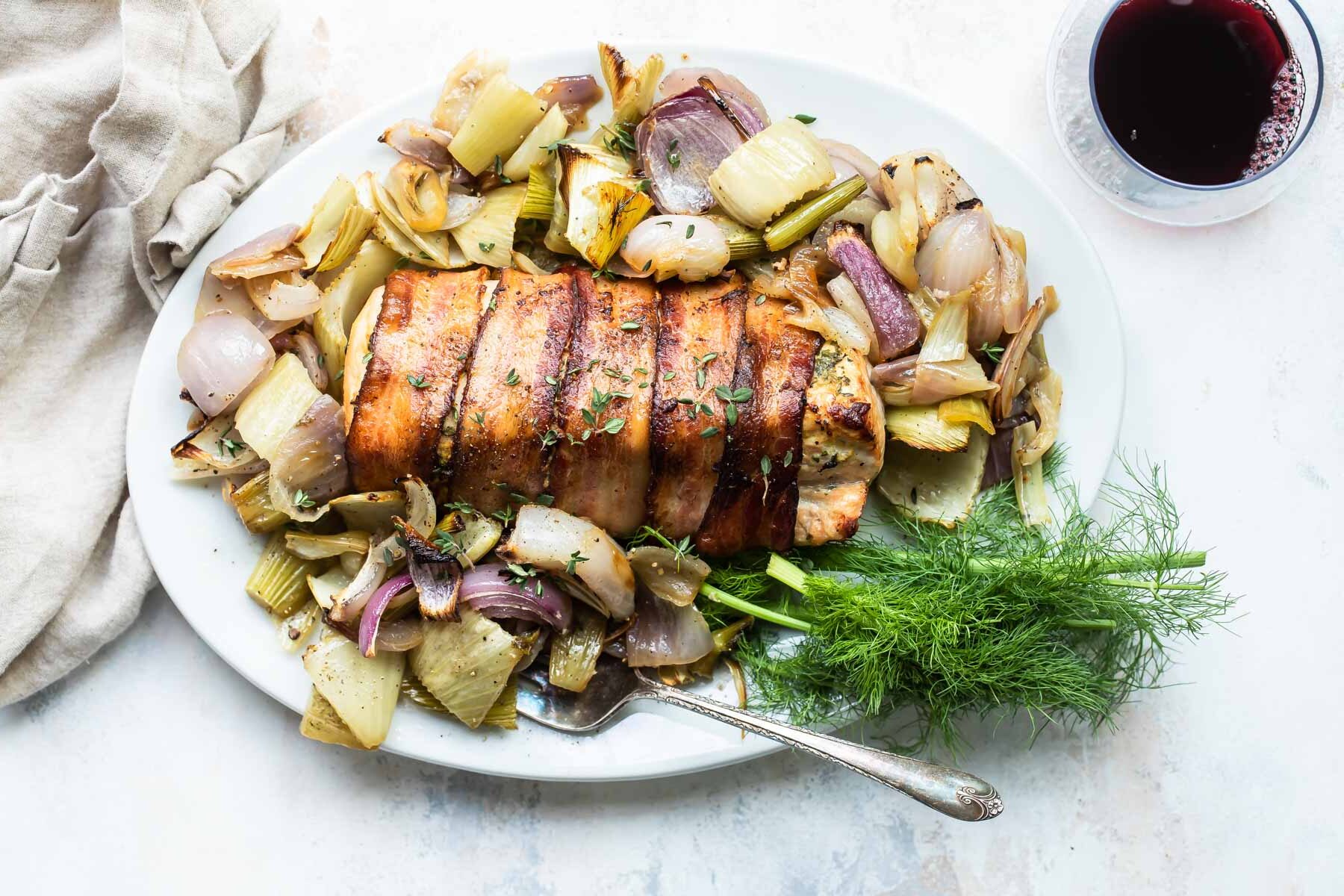 Bacon wrapped pork tenderloin on a gray plate.