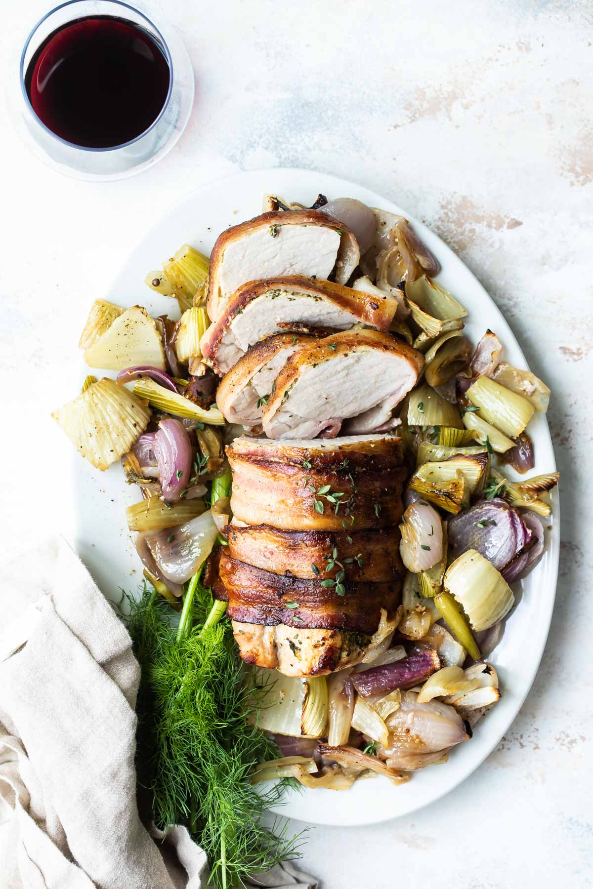 Bacon wrapped pork tenderloin on a gray plate.