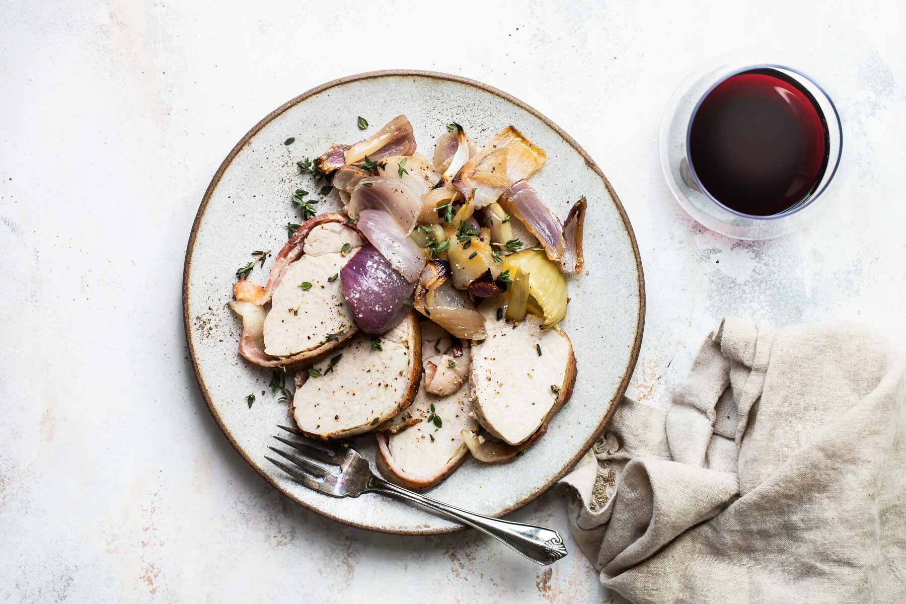 Bacon wrapped pork tenderloin on a gray plate.