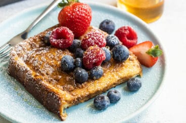 Baked french toast on a plate covered with berries.