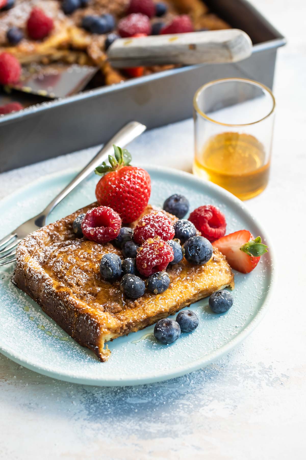 Baked french toast on a plate covered with berries.