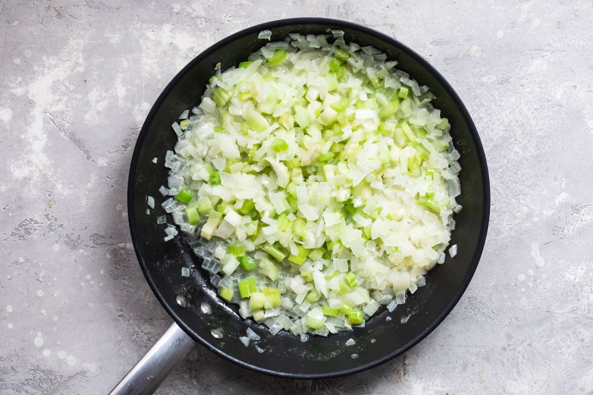 Onion and celery cooking in a skilet.