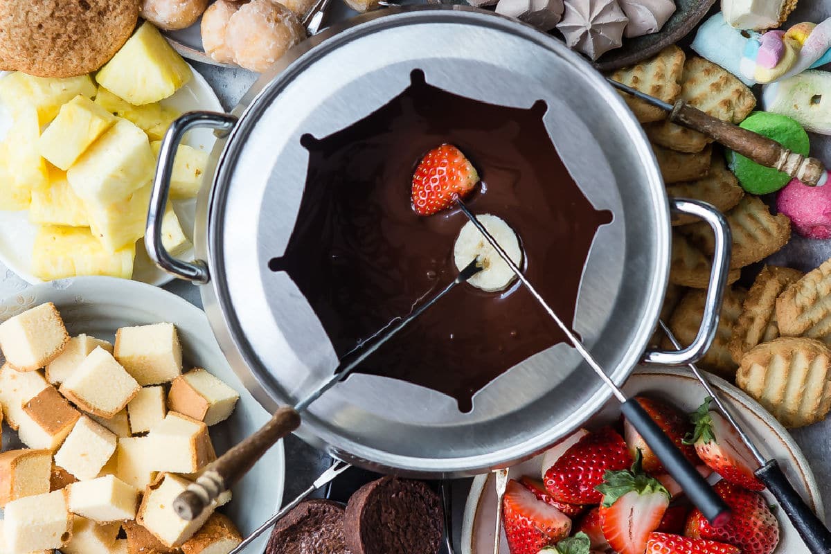 Chocolate fondue served with candy, cookies, cake, and fresh fruit.