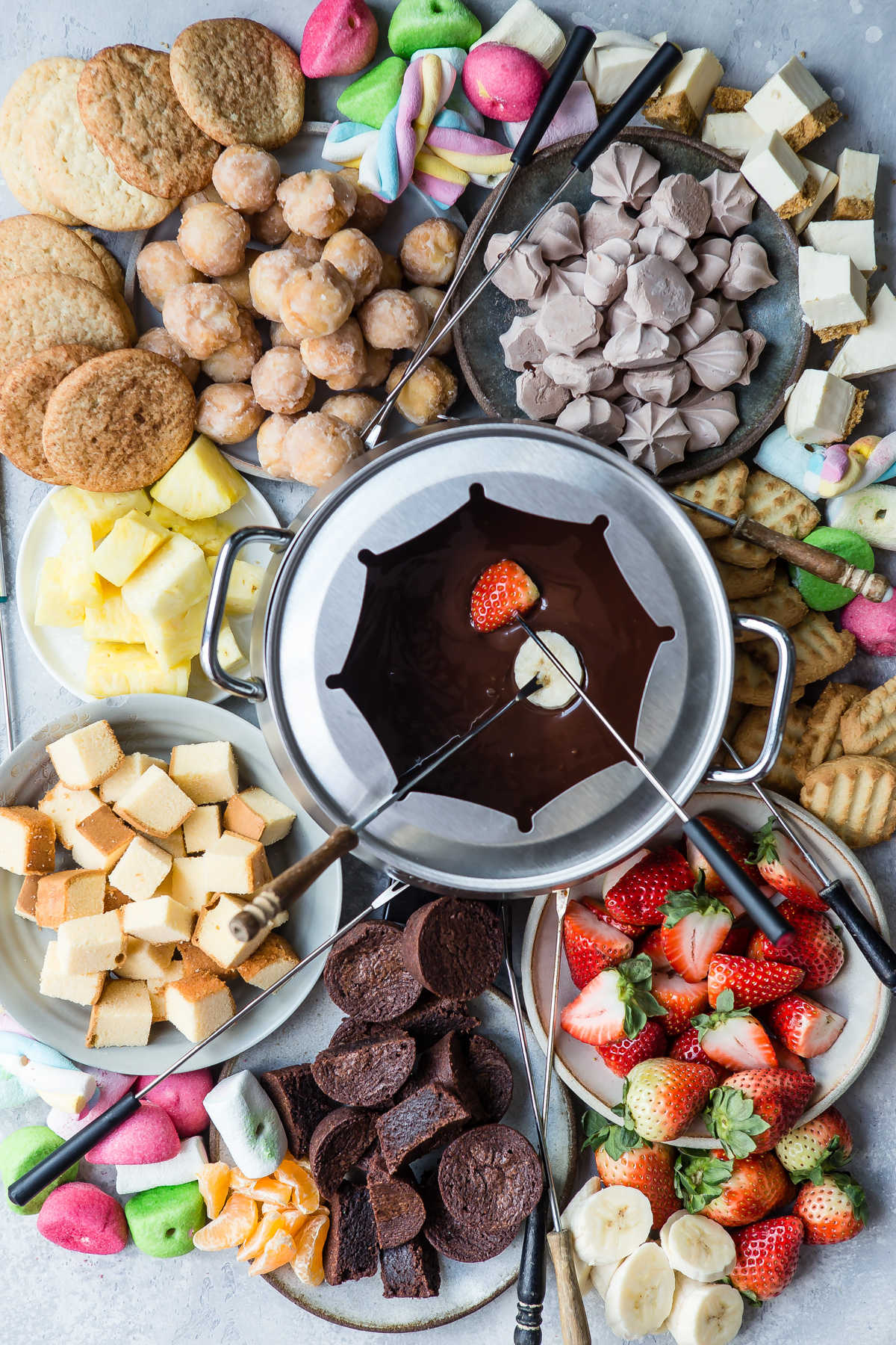 A platter of chocolate fondue and colorful dippers like fruit and sweets.