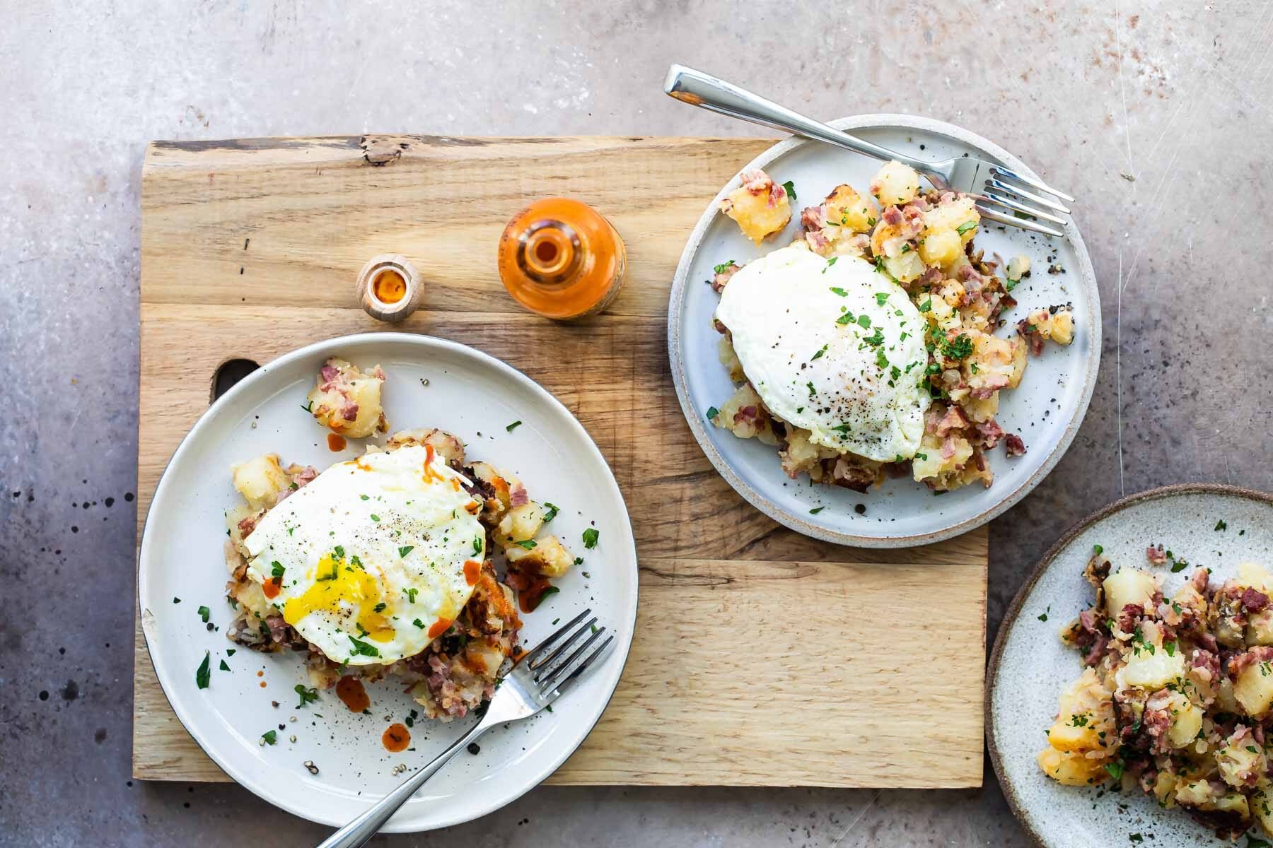 Corned beef hash on a gray plate topped with and egg and parsley.