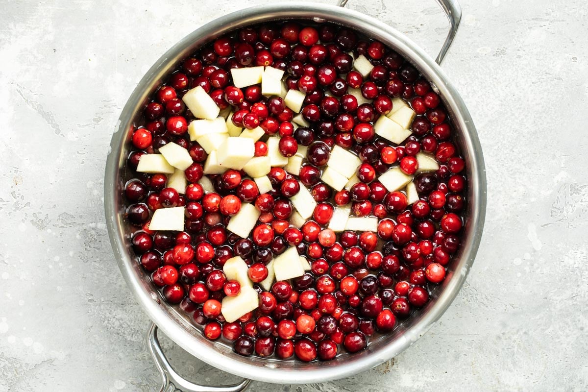 Cranberries and apples cooking in a saucepan.