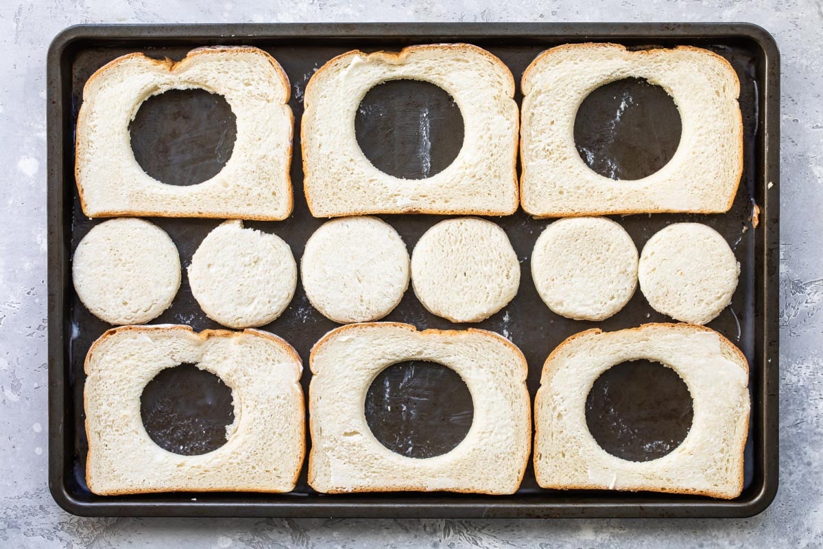 Eggs in a basket cooking on a sheet pan.