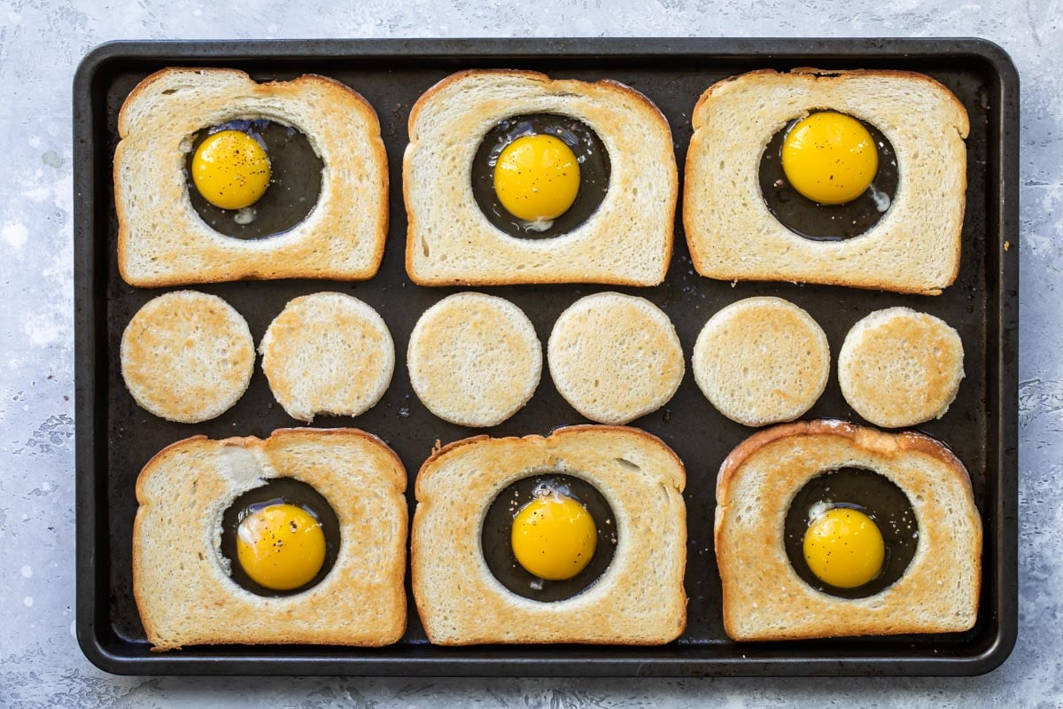 Eggs in a basket cooking on a sheet pan.