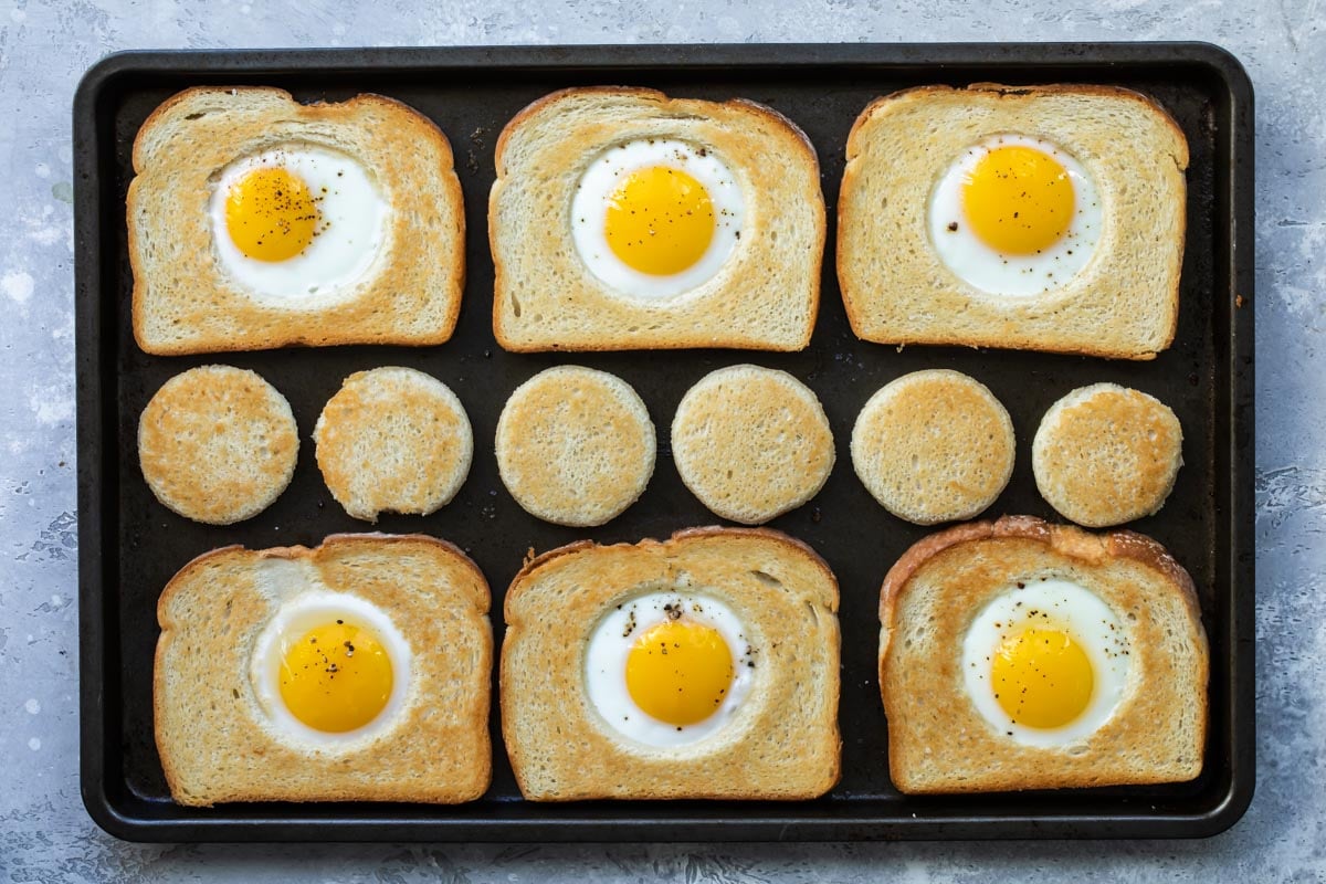 Eggs in a basket cooking on a sheet pan.