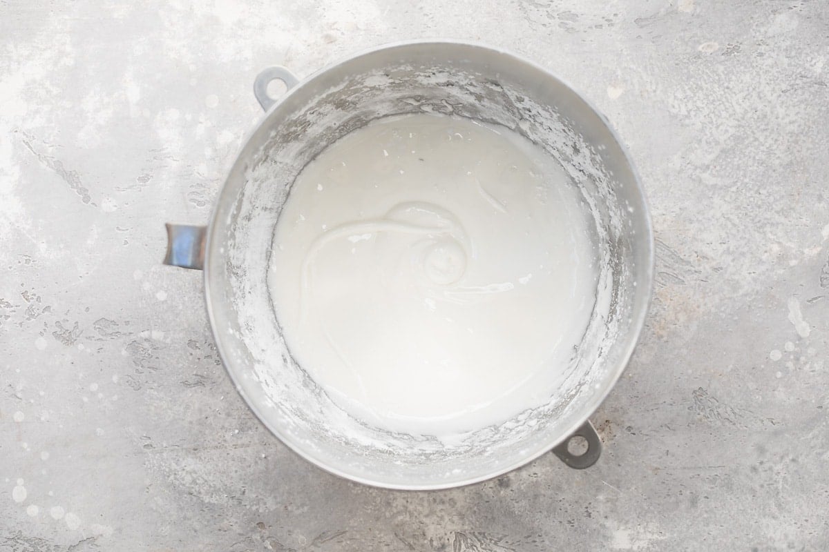 Frosting ingredients mixed together in a silver mixing bowl.