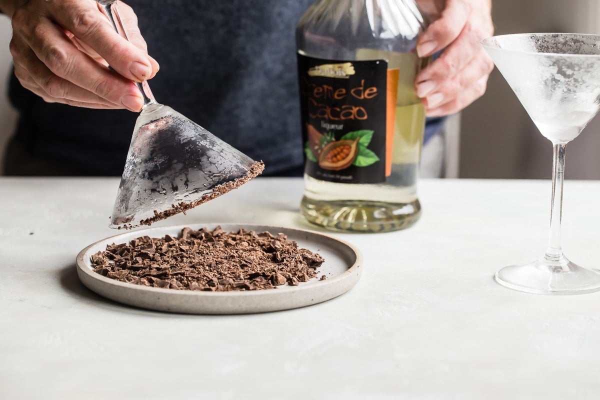 Rimming a martini glass with chocolate shavings.