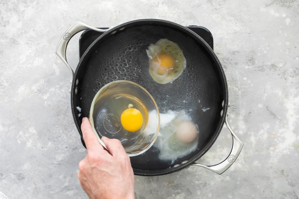 Dropping eggs into vinegar water for poaching.
