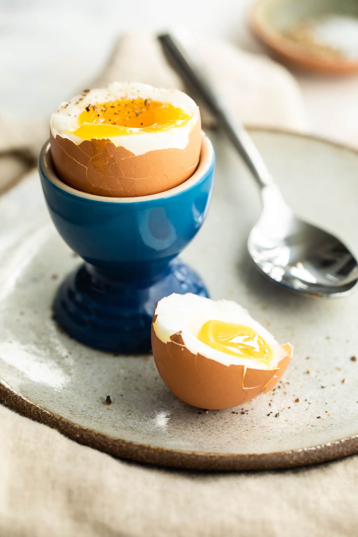 A soft boiled egg in a blue egg cup with toast sticks next to it.