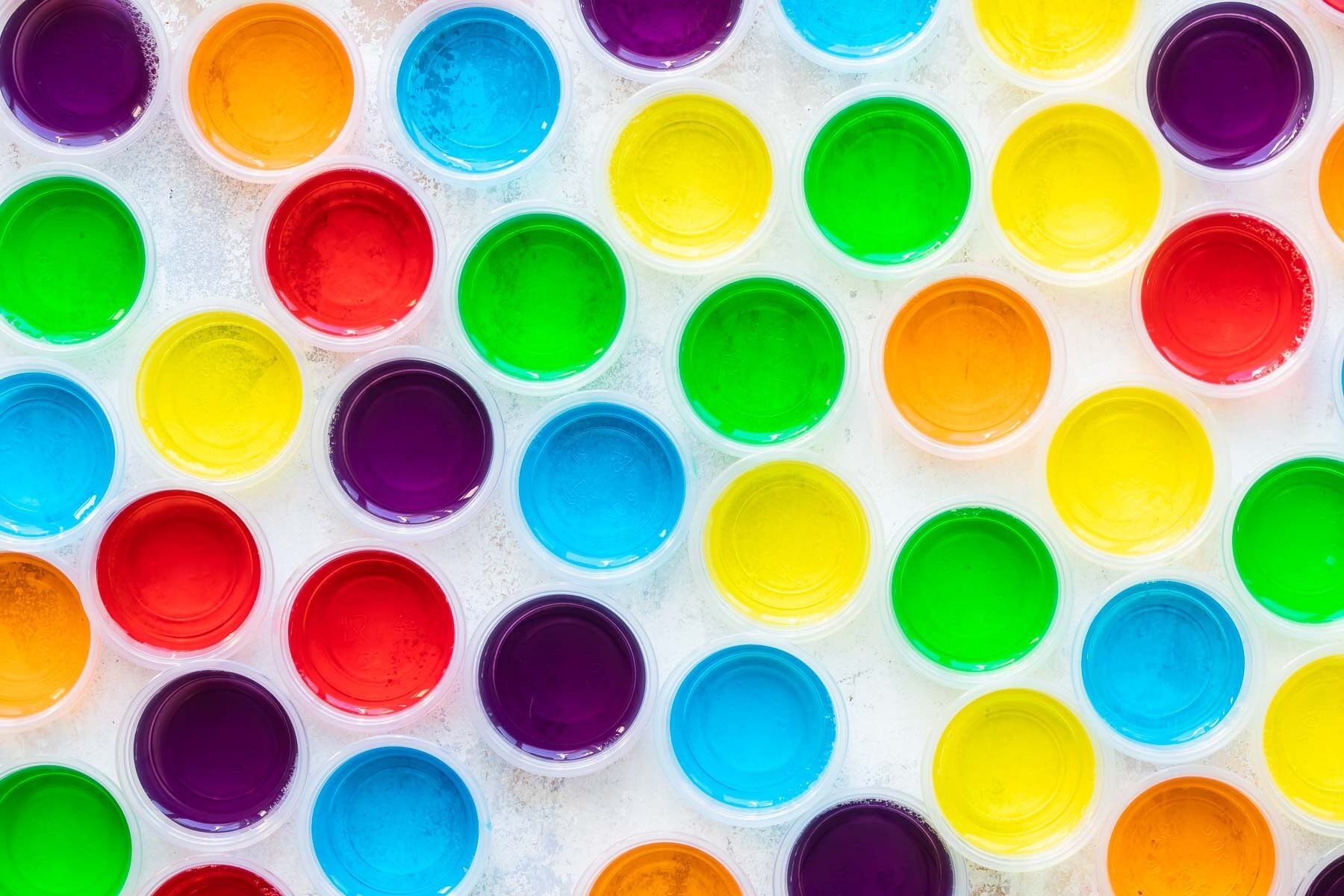 Various colored jello shots in clear portion cups.