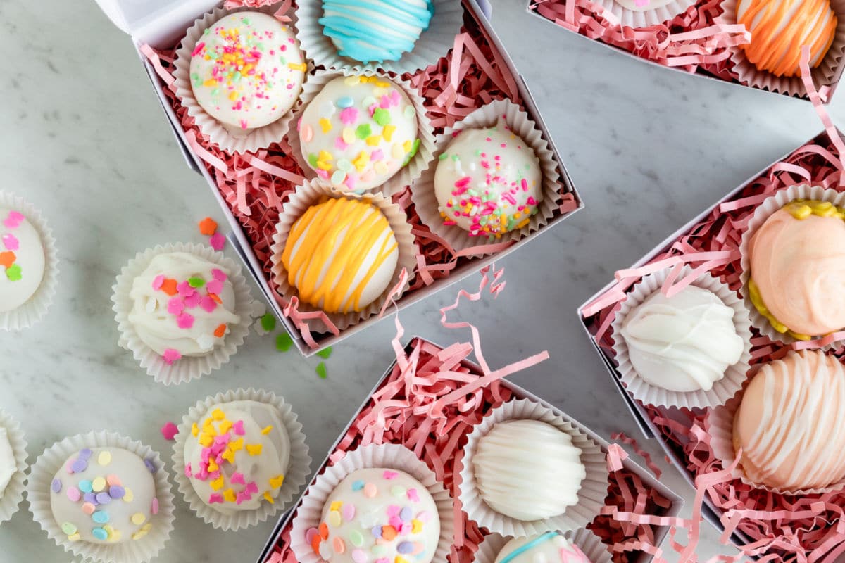 Lemon cookie balls decorated and arranged in gift boxes on a table.
