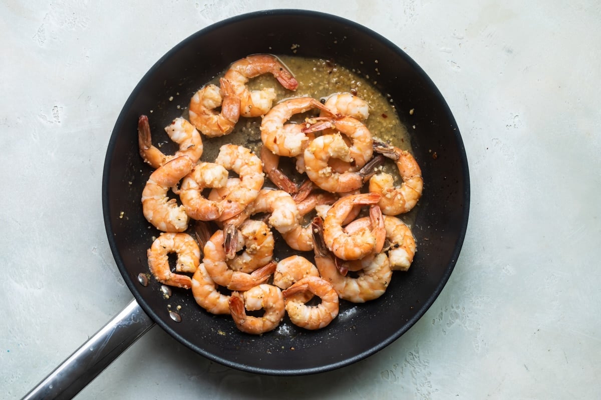 Cooked shrimp in a black skillet.
