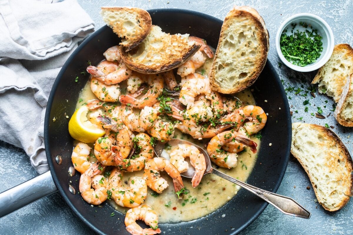 Shrimp scampi in a black skillet.