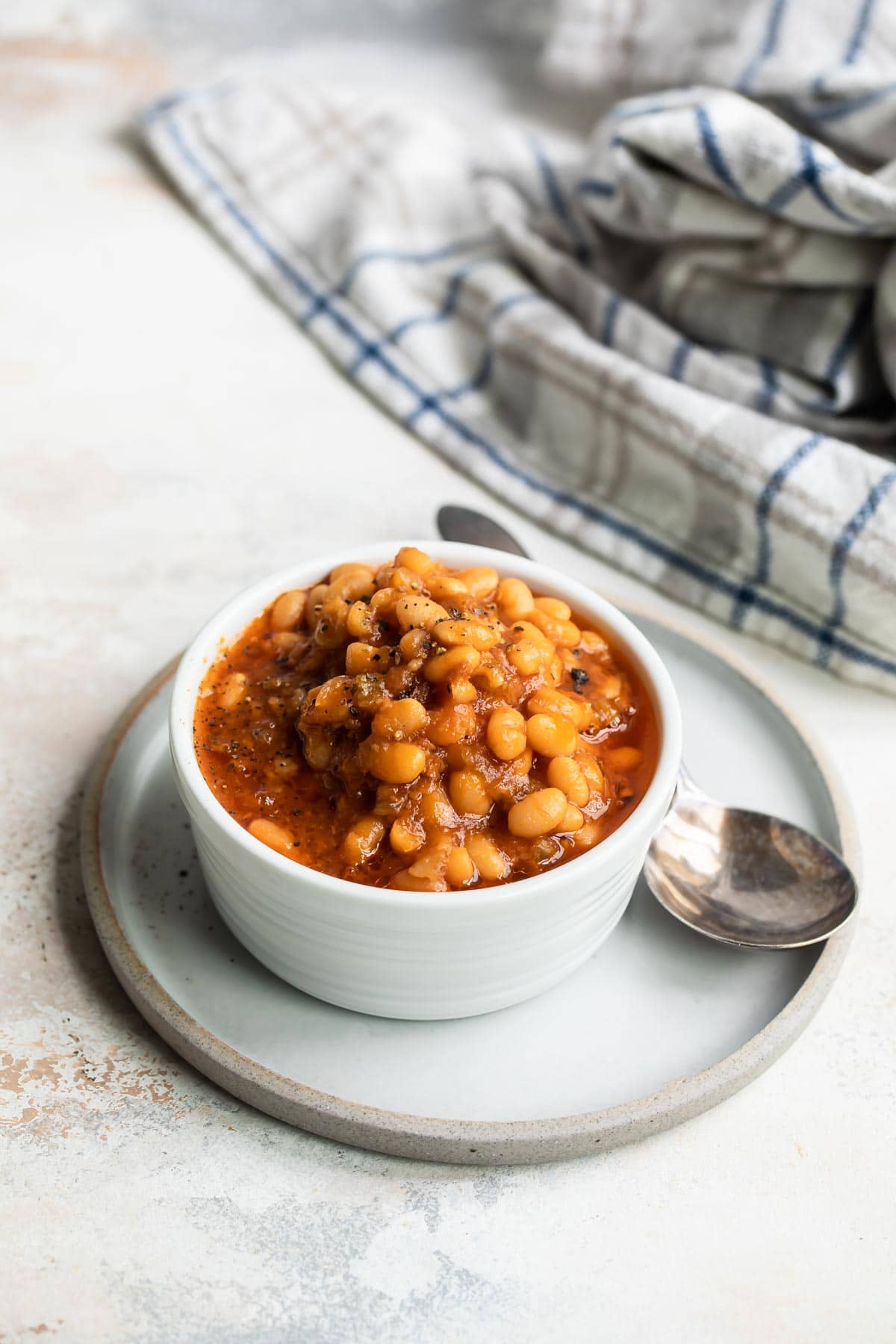 Slow cooker baked beans in a small white bowl.