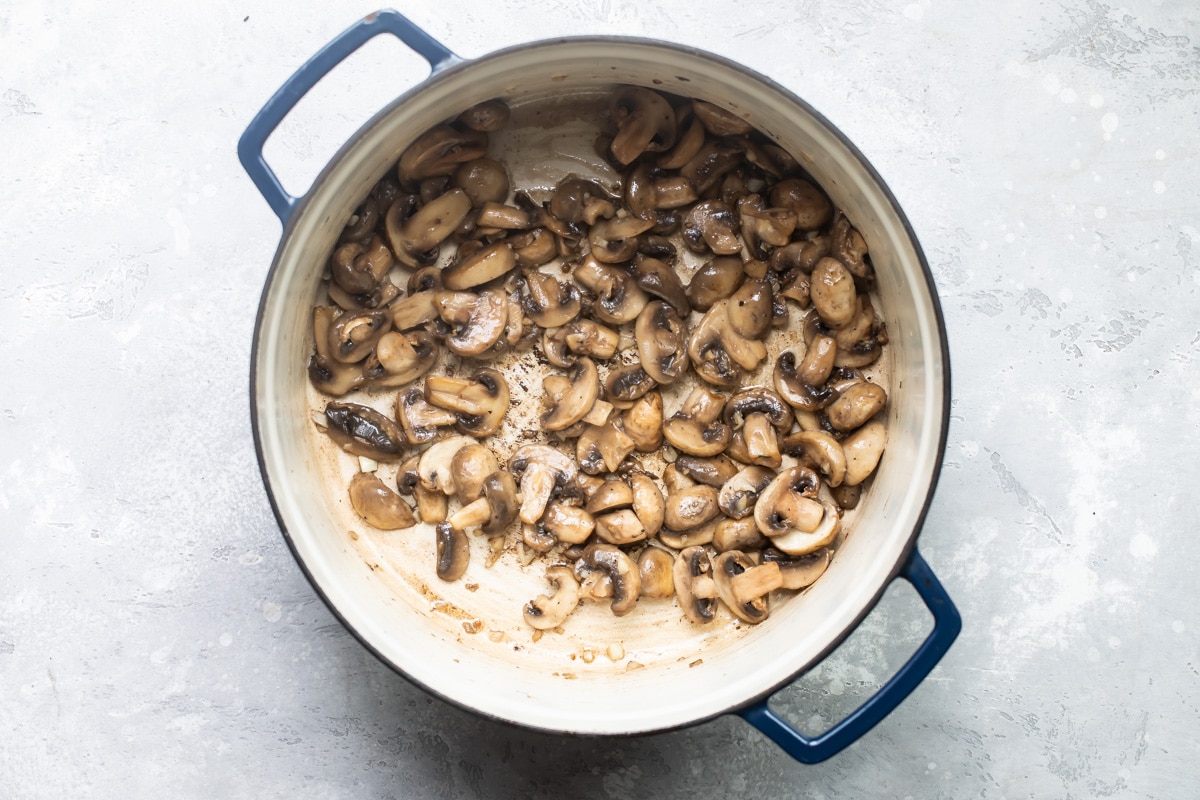 Mushrooms cooking down in a stock pot.