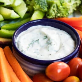 Veggie dip in a small navy blue bowl surrounded by vegetables.