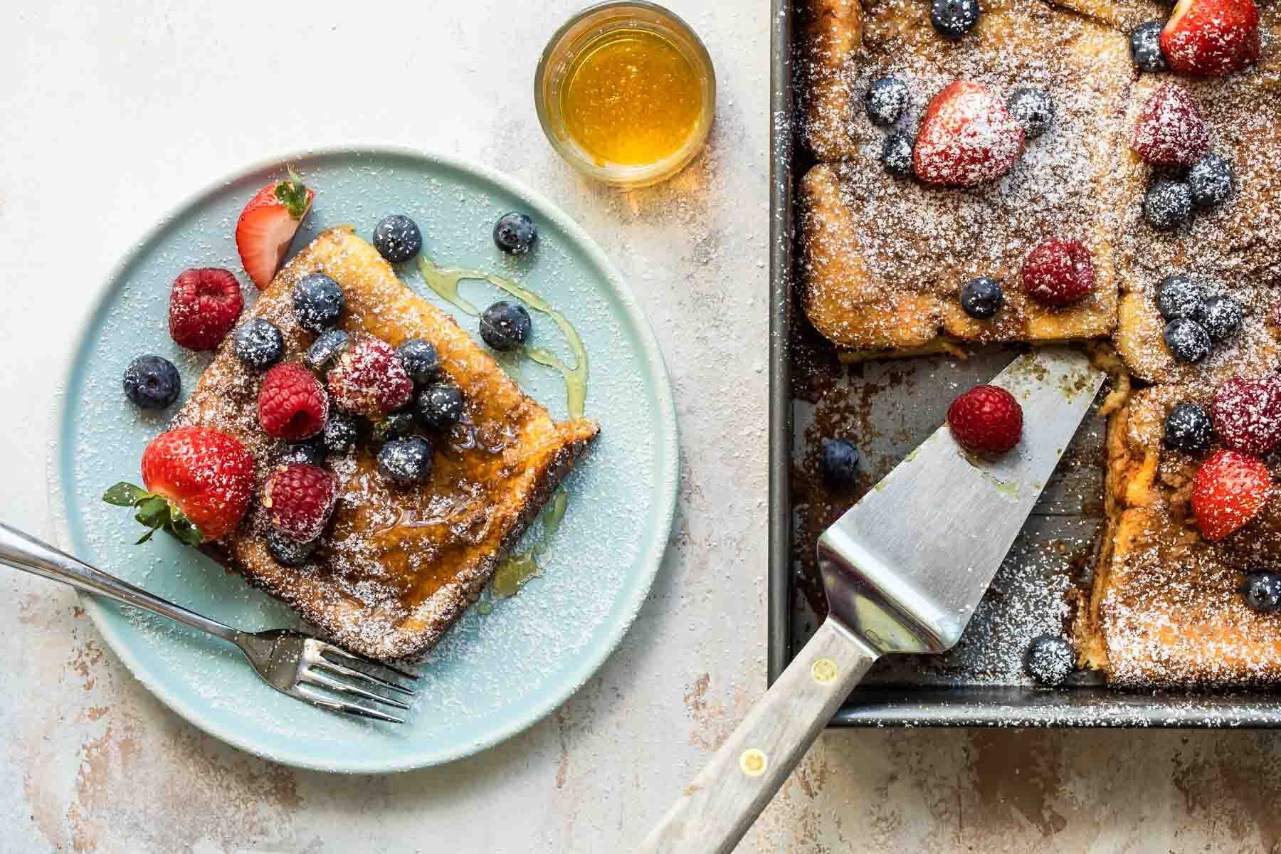 Baked french toast on a plate covered with berries.