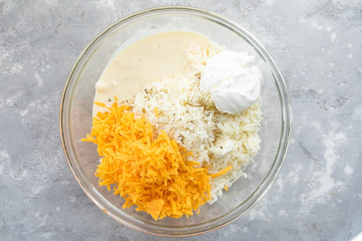 Cheesy potato casserole ingredients in a bowl before mixing.