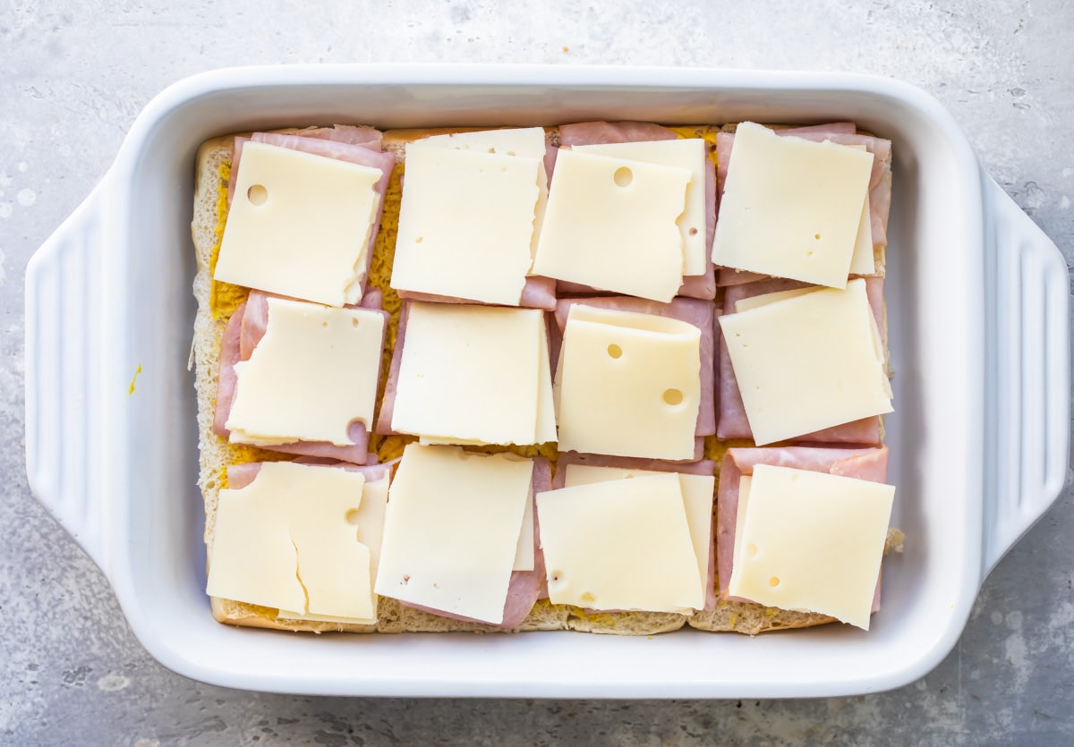 Building ham and cheese sliders in a baking dish. 