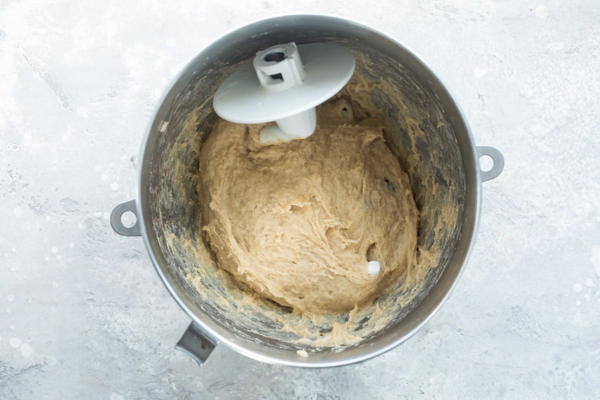Hot cross bun dough in a silver mixing bowl.