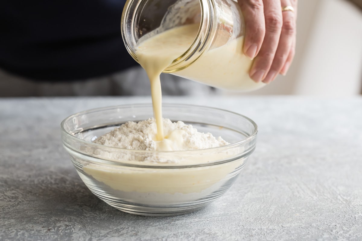 Someone pouring liquid into dry ingredients for Irish Soda Bread.