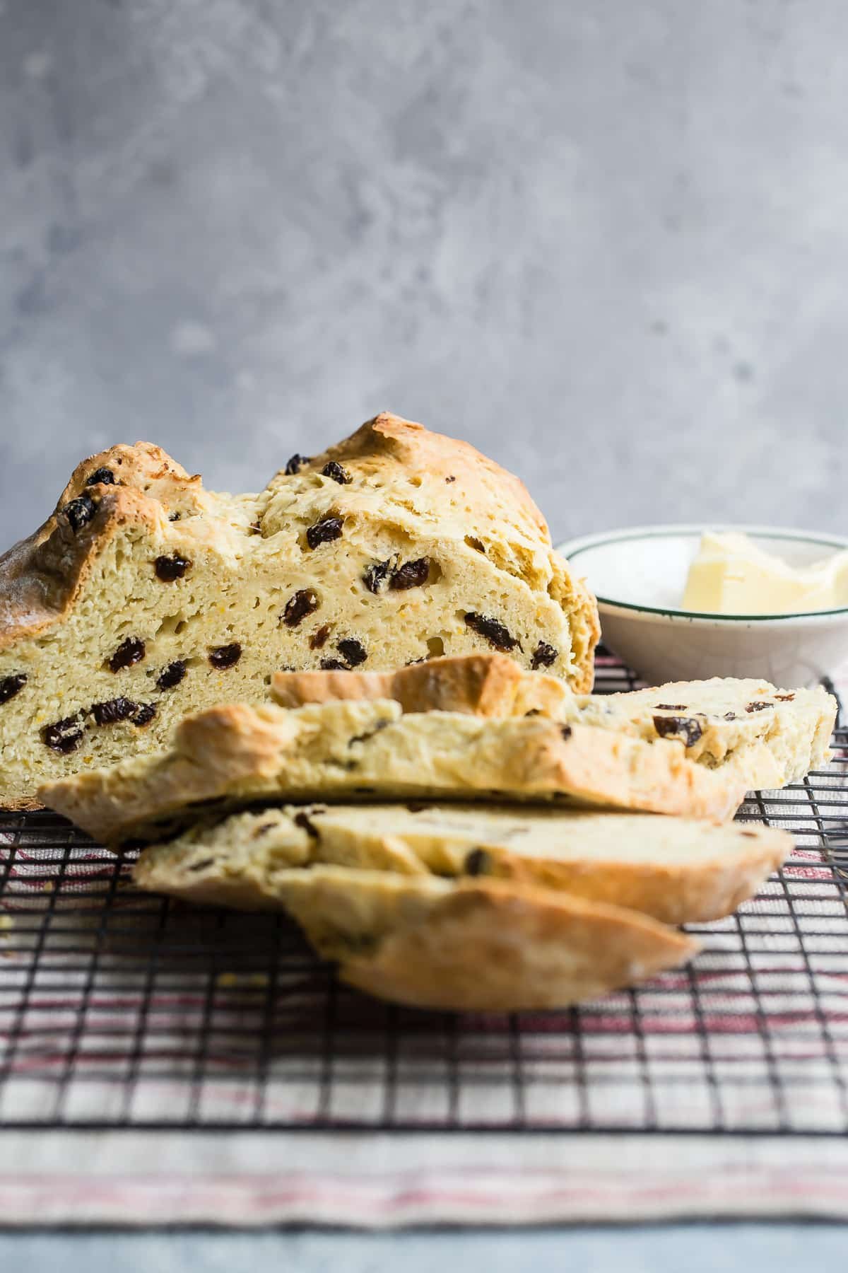 A loaf of Irish soda bread on a wire rack with some slices cut.