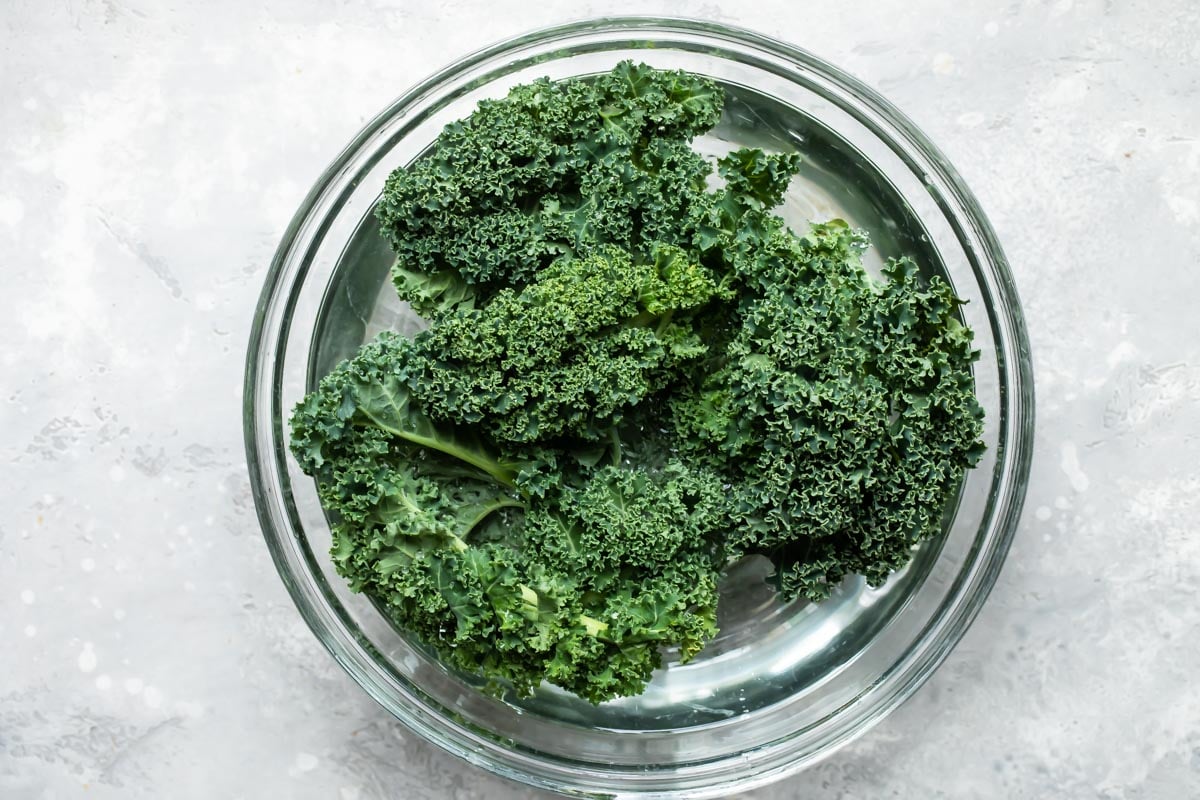 Cleaning kale in a bowl of water.