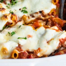 A pan of baked ziti with a spoon in it.