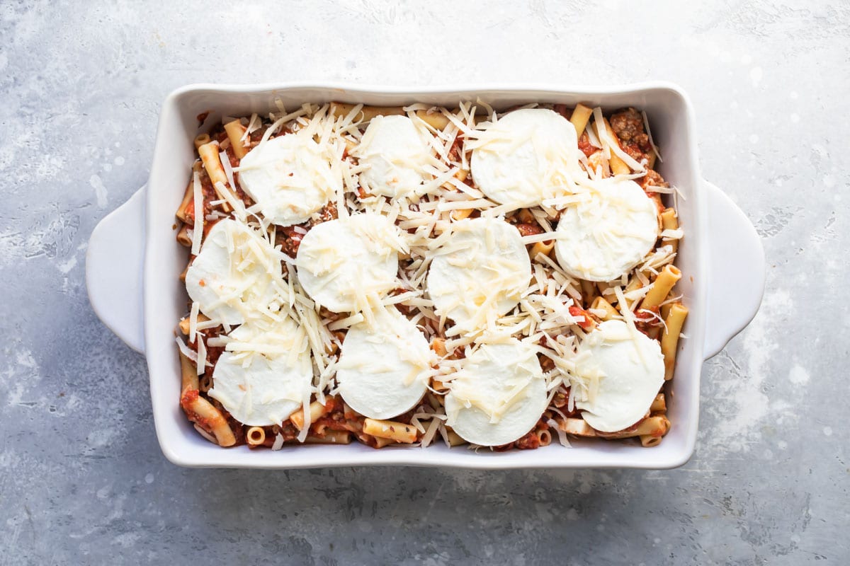 Baked ziti in a white baking dish before being baked.