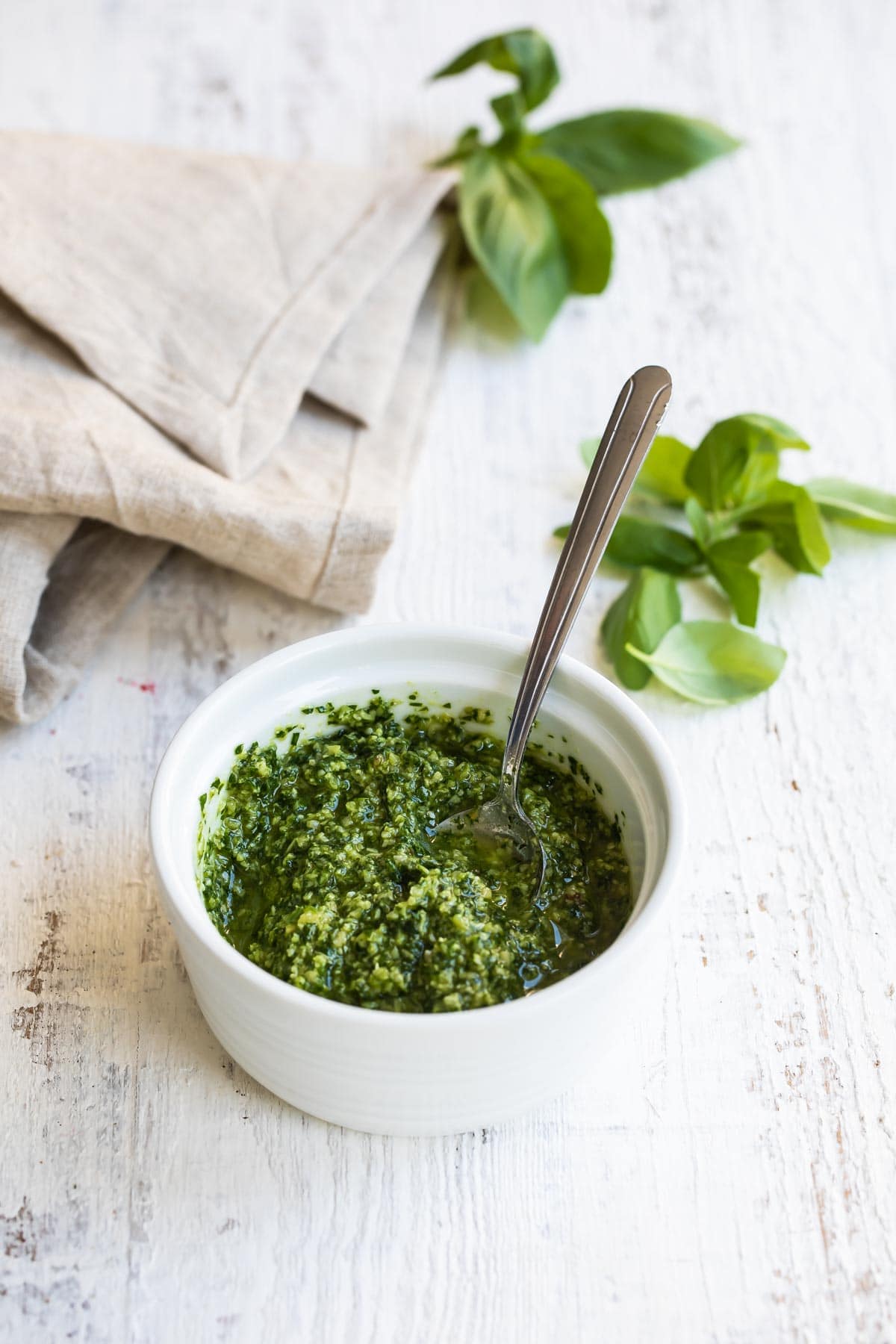 A bowl of pesto with a spoon in it.