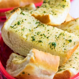 Garlic bread in a plastic red basket.