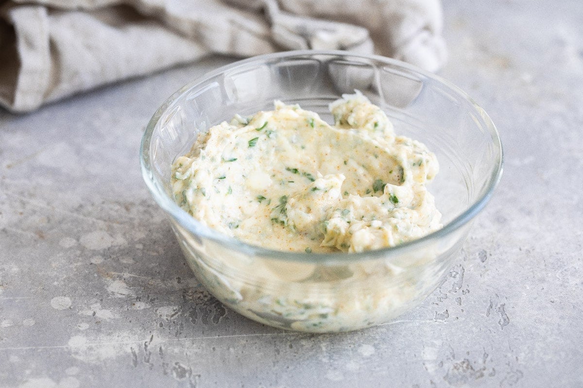 A clear bowl with some garlic spread in it.