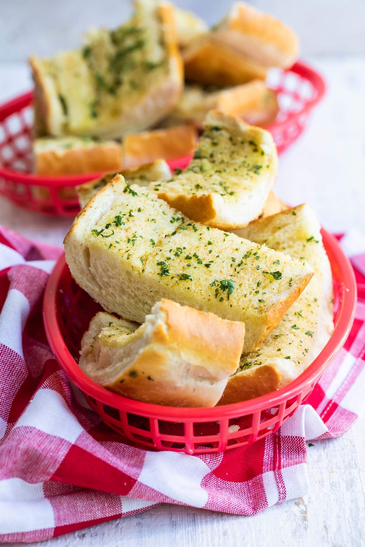 Garlic bread in a plastic red basket.