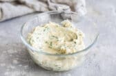 A clear bowl with some garlic spread in it.
