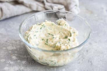 A clear bowl with some garlic spread in it.