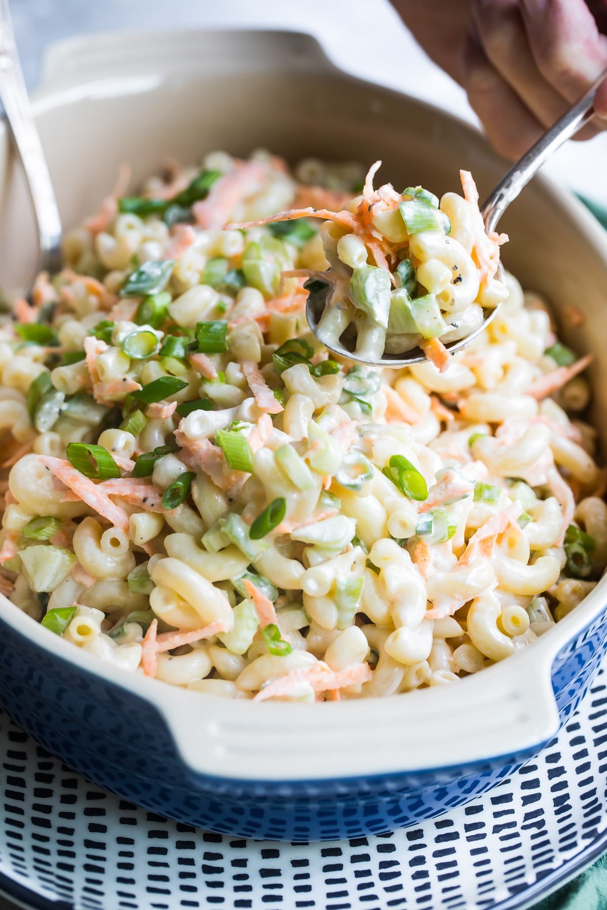 Hawaiian Macaroni Salad being scooped out of a blue serving dish.
