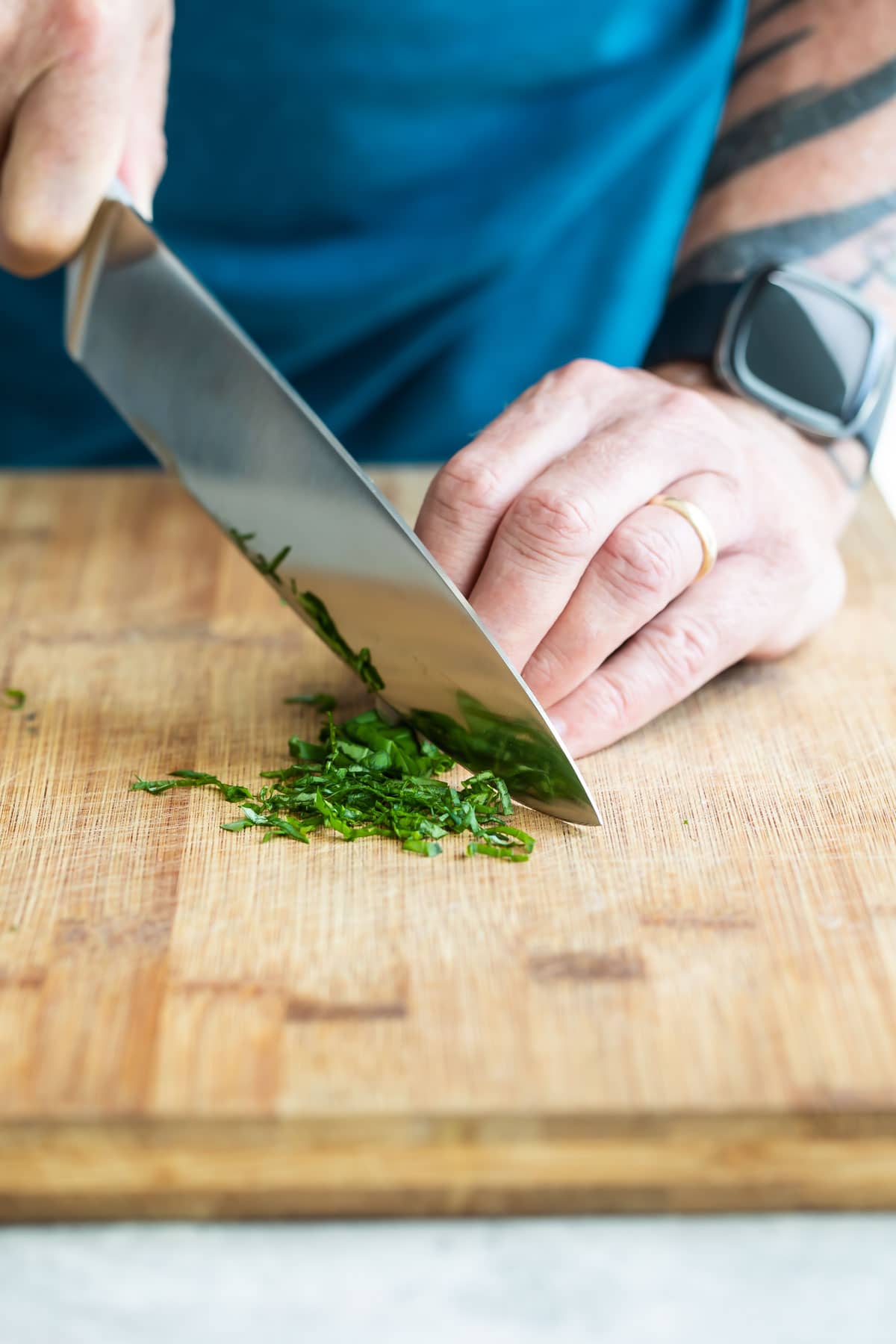 Someone chiffonading basil on a cutting board.