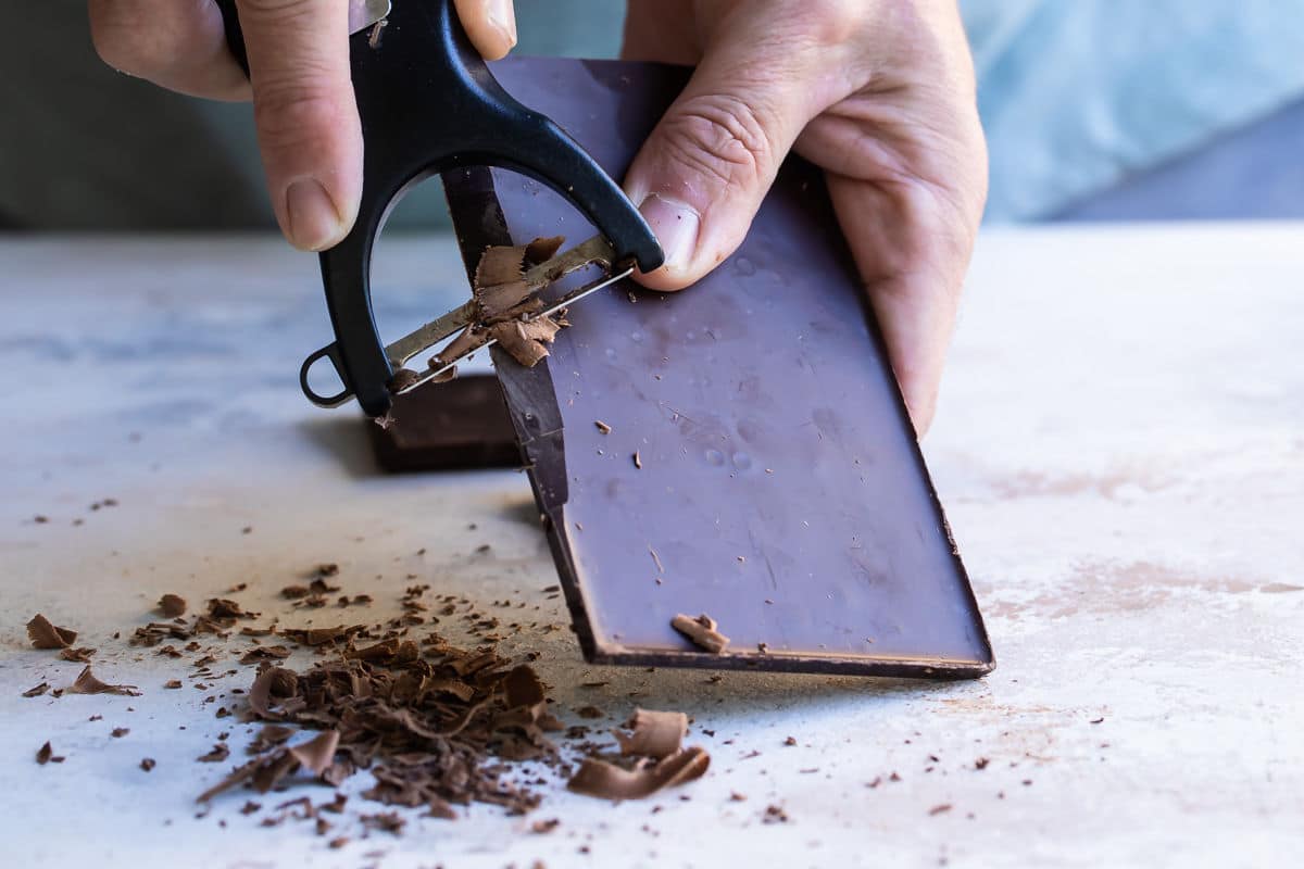 Shaving chocolate curls off a bar of chocolate.