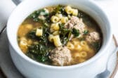 Italian wedding soup in a white bowl.