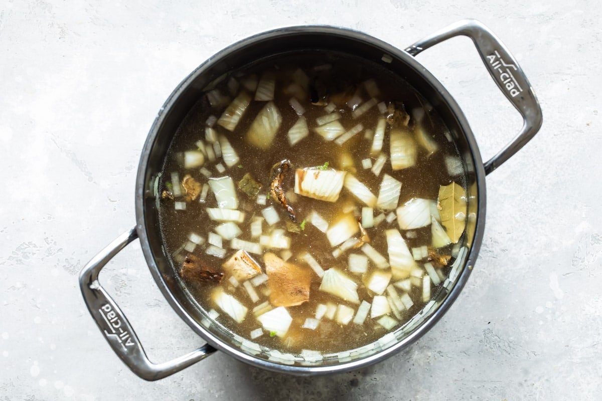 A stock pot with vegetables and broth in it.
