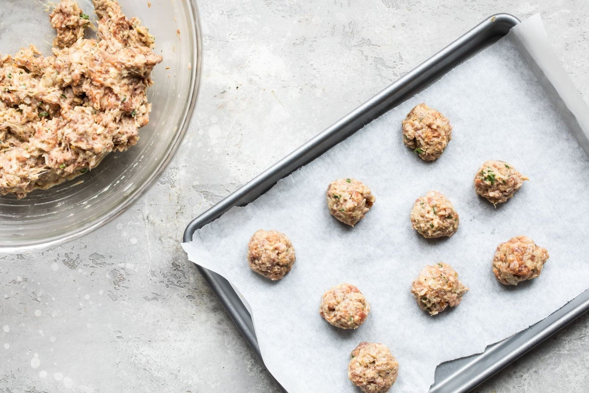Meatballs on a parchment paper lined baking sheet.