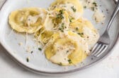 A plate of mushroom ravioli and a glass of white wine.