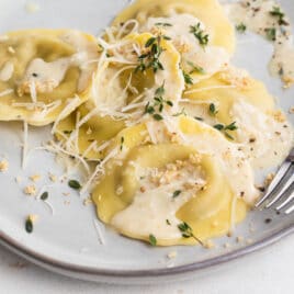 A plate of mushroom ravioli and a glass of white wine.