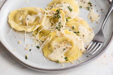 A plate of mushroom ravioli and a glass of white wine.